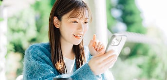 若い女性がスマートフォンでネットショッピングをしているイメージ画像